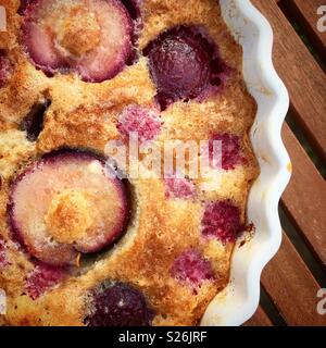 Pflaume und Himbeere Biskuitboden in quiche Teller draußen auf Picknick Tisch Stockfoto