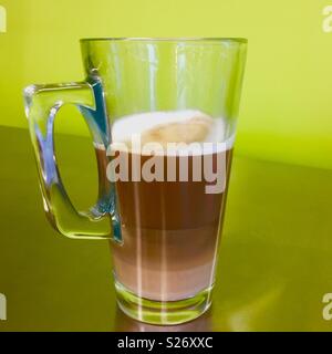 Caffé latté mit mehreren Ebenen in einem Glas Schale auf grünem Hintergrund Stockfoto