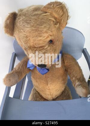 Vintage Teddybär setzte sich in einem vintage Holz Hochstuhl Stockfoto