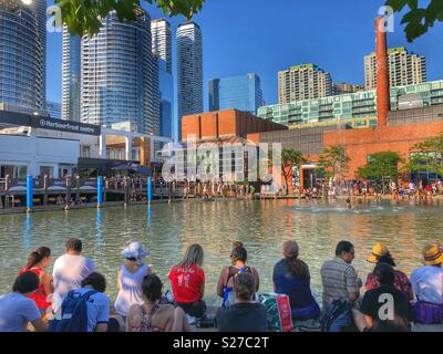 Menschen rund um den Natrel Teich sitzen an Harbourfront Centre an einem heissen Sommertag in Toronto. Stockfoto