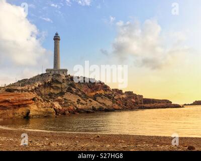 Historische "Faro de Cabo de Palos " Leuchtturm kurz nach Sonnenaufgang von der nahe gelegenen Strand gesehen. La Manga del Mar Menor, Cartagena, Spanien Stockfoto