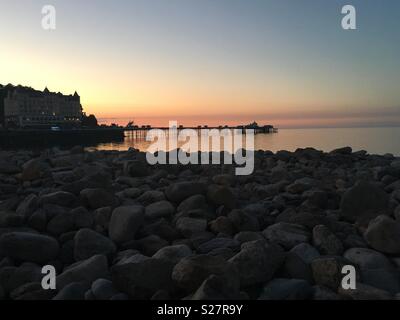 Llandudno Pier bei Sonnenuntergang - vom Kiesstrand entfernt. Stockfoto