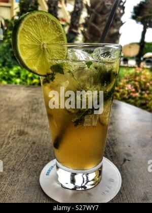 Mojito Cocktail mit frischen Kalk und gemahlen Minze in ein hohes Glas mit einem Kunststoff Stroh; Tischplatte Stockfoto