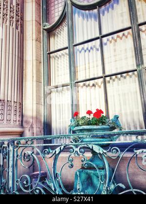 Kupfer Blumentopf mit roten Blumen auf Kupfer Balkon nach Spalte Stockfoto
