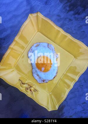 Ein Spiegelei auf gelbem Schild mit blauem Hintergrund Stockfoto