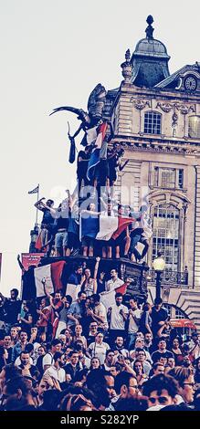 Französische Fußball-Fans mit der Französischen Flagge (tricolor) klettern Eros statue Frankreichs 2018 World Cup zu feiern gewinnen, Piccadilly Circus, London Stockfoto