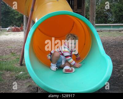 Kleines Mädchen unten kommt ein Rohr schieben Stockfoto