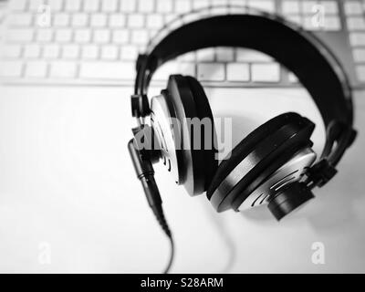 Schwarz und Weiß professioneller Kopfhörer mit unscharfen Computer Tastatur im Hintergrund. Selektive konzentrieren. Musik und Entspannung Konzept Stockfoto