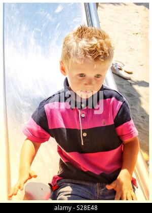 Junge auf einer Folie in einem Spielplatz am Strand Stockfoto