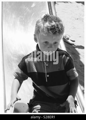 Junge eine Folie in einem sandspielplatz Stockfoto