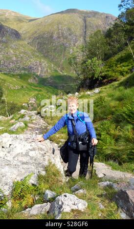 Reife weibliche Wanderer klettern in das verlorene Tal von Glencoe, Schottland, UK Stockfoto