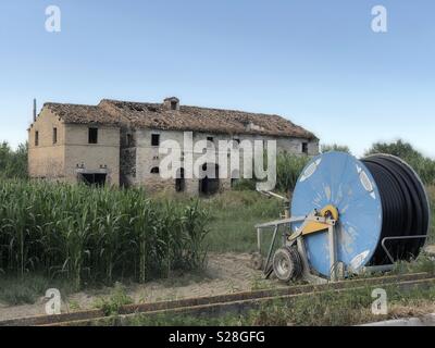 Bewässerung Maschine vor einer typischen Region Marche Country House im Naturpark der Sentina, Italien verlassen Stockfoto