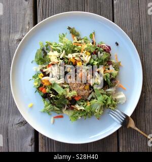 Blick von oben auf italienische Pasta Salat, Kopfsalat, orzo, Oliven, Paprika, Thunfisch, weißer Teller auf Verwittertem Holztisch Stockfoto