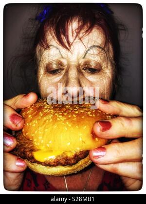 Ältere Frau essen Käse Burger Stockfoto
