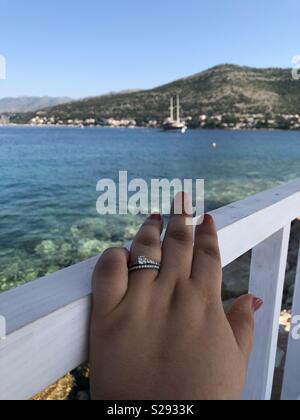 Eine Frau mit Engagement Ring und Hochzeit Band auf einer Cabana Geländer mit Blick auf die Adria in Kroatien. Stockfoto