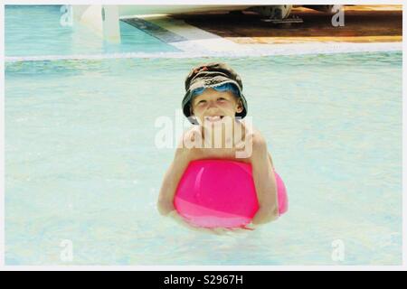Junge in Pool lehnte sich auf einem Strand Ball Stockfoto