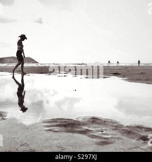 Reflexionen zu Fuß auf einem Strand in Polzeath, Cornwall Stockfoto