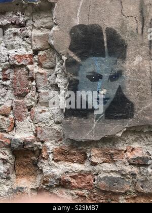 Schwarz und Weiß Schablone Kunst, das Porträt einer jungen Frau, die auf einem zerbröckelnden Mauer mit Beton machen, in der polnischen Stadt Krakau. Stockfoto