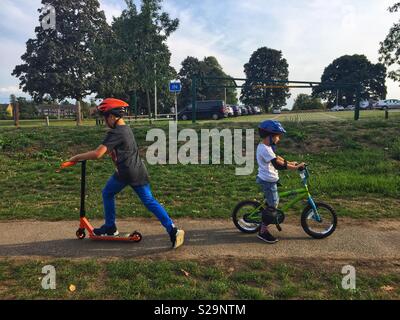 Brüder, ihre Fahrräder und Motorroller im Park. Stockfoto