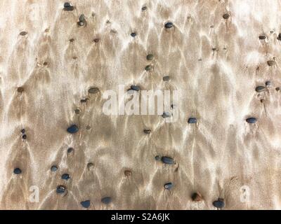 Pebbles und Wind sand Muster auf einem Waliser Strand geblasen. Stockfoto