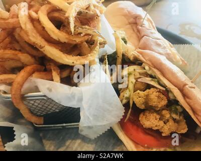 Eine gebratene Oyster Po'boy und Curly Fries. Stockfoto