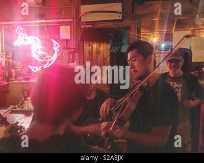 Japanische Geiger Kensuke Shoji genießt eine letzte Fiddle tune für die Straße nach dem Samstag Nacht bluegrass Jam auf der sonnigen Bar in Red Hook in Brooklyn. Stockfoto