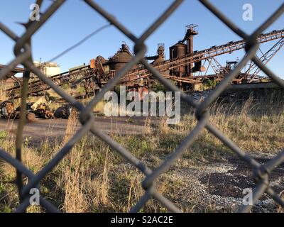 Rostig und verlassenen Stahlwerk Schuß durch einen Maschendrahtzaun in Georgetown, South Carolina. Stockfoto