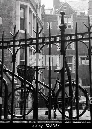 Lincoln's Inn, London, England - Altmodische Fahrrad, hinter einem Geländer, im Regen Stockfoto