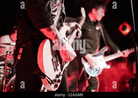 Gitarristen in einer Punk Band auf der Bühne bei einem Konzert. Gitarre und tätowiert Arm Stockfoto