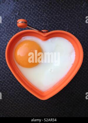 Spiegeleier, gebratenen Braten in der Pfanne. Die Eier ist in der Form eines gesunden Herzens eine gesunde Ernährung und gutes Wohlbefinden zu implizieren. Stockfoto