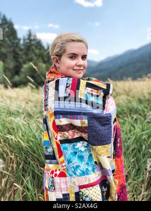Mädchen verpackt in Modern Quilt Decke in der Wiese Stockfoto