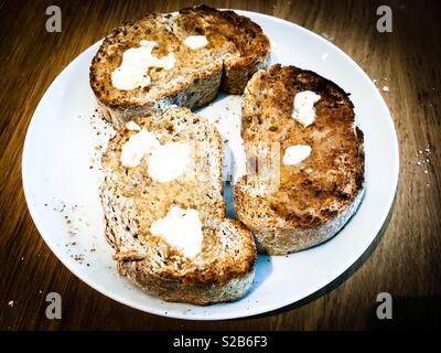 Drei Scheiben Vollkornbrot und Butter Toast auf eine weisse Platte Stockfoto