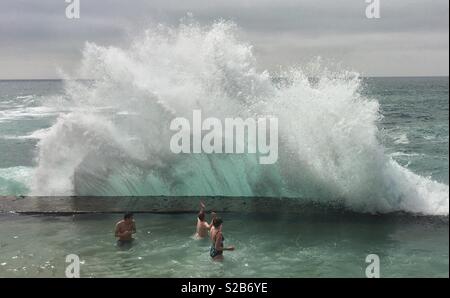 Riesige Wellen brechen über Sea Wall in Meer Pool über 3 Menschen in Portugal Stockfoto