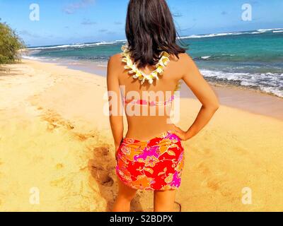 Attraktive junge Frau auf einsamen tropischen Insel Strand mit Blumen plumeria Lei, brünette Haare, rosa Bikini Stockfoto