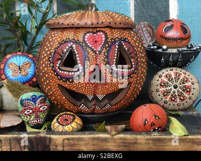 Eine Anzeige von Halloween und Herbst Artwork mit einem terra-cotta jack o lantern und etwas Zucker Schädel und Mandala Felsen in den Farben der Saison. Stockfoto