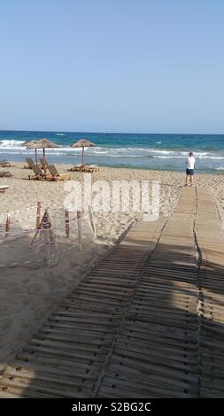 Mann, der an einem Strand mit Blick aufs Meer in Kreta Stockfoto
