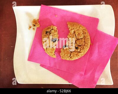 Oatmeal raisin Cookies in der Hälfte auf einem Rosa Serviette und weiße Platte angezeigt Split Stockfoto