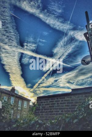 Flugzeug Kondensstreifen, kreuz und quer durch den Himmel über East Finchley, London Kreuz Stockfoto
