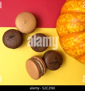 Herbst Genuss - Handgefertigte bunte Macarons zu den roten und gelben Hintergrund mit Kürbis Stockfoto