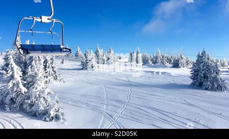 Winterlandschaft mit leeren Skilift Stuhl von atemberaubenden Nadelbäume und Skipisten und schönen blauen glänzenden Himmel umgeben. Stockfoto