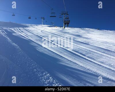 Winterlandschaft auf der schönen, sonnigen Tag am Berg mit Skilift oberhalb der verschneiten Piste. Stockfoto