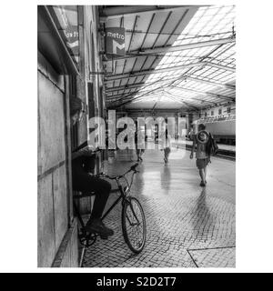 Homem numa bicicleta na Estação de Comboios de Santa Apolónia em Lisboa. Estação da CP, Comboios de Portugal. Einen Menschen steht in einem Fahrrad am Bahnhof Santa Apolónia Stockfoto