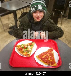 Neun Jahre alten Jungen mit zwei großen Pizza Scheiben, Boston, Massachusetts, Vereinigte Staaten von Amerika. Stockfoto