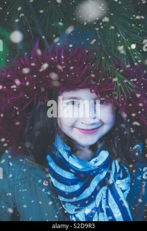 Schöne junge Mädchen mit roten Haube stand in den Wald mit Schnee leise rund um fallen. Weihnachten, Winter Szene moderne Rotkäppchen. Wald im Schnee. Stockfoto