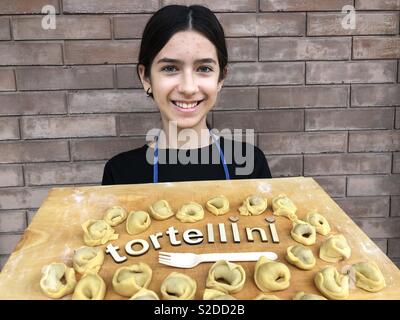 Junges Mädchen mit hausgemachten Tortellini, traditionelle italienische gefüllte Nudeln auf einem Holzbrett Stockfoto