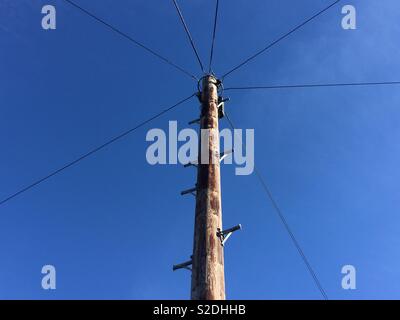 Telegraphenmast und die Drähte vor einem klaren blauen Himmel Stockfoto