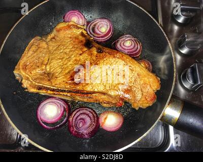 Waitrose britisches Rindfleisch mit Knochen Sirloin Steak in der Pfanne gebratener mit roten Zwiebeln Stockfoto