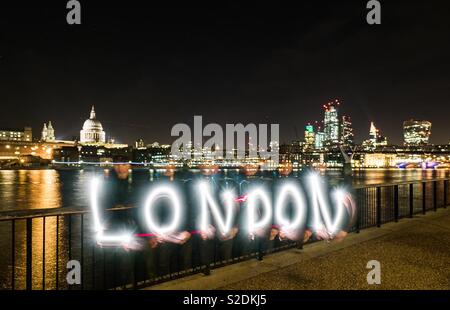 St. Paul's und der Square Mile von der South Bank in der Nacht mit dem Wort London im Licht im Vordergrund lackiert Stockfoto