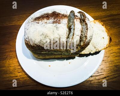 Laib Weißbrot in Scheiben geschnitten auf einer weißen Platte Stockfoto