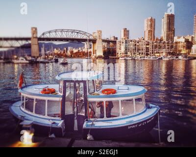 Granville Island Fähren Wassertaxi "der Geist von Cy Balfry" an der Granville Island, Sonnenuntergang angedockt, mit der Burrard Street Bridge im Hintergrund. False Creek, Vancouver, British Columbia, Kanada Stockfoto